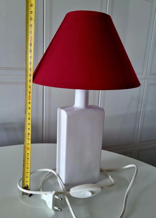 Candeeiro de mesa, feito com uma garrafa branca e abajour vermelho.