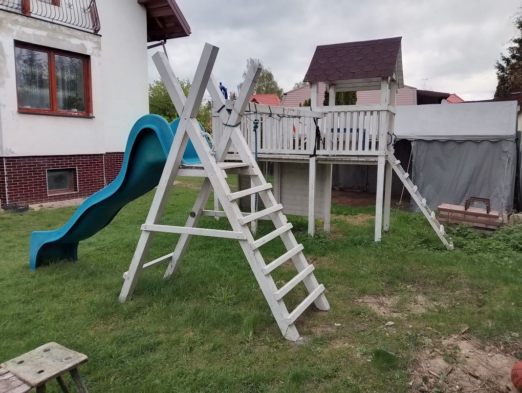 Plac zabaw Żeglarski domek drewniany i zjeżdżalnie z huśtawkami.