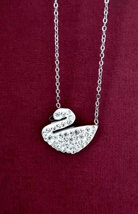 Colar prateado, em aço, com pingente em forma de cisne branco.