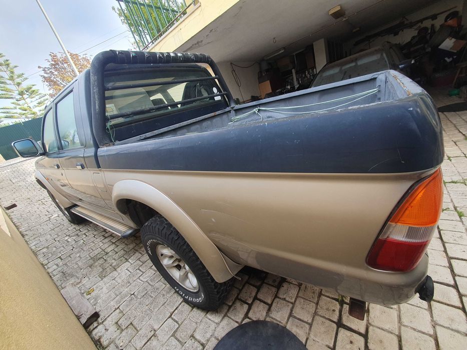 Mitsubishi L200 preta e prateada com engate de reboque