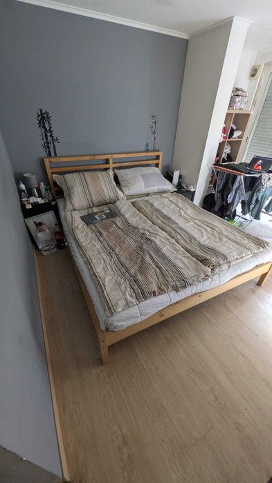 Uma cama de casal com estrutura de madeira (180x200 cm).