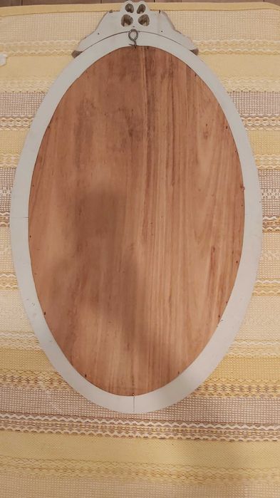 Espelho biselado com moldura de madeira com detalhes esculpidos.