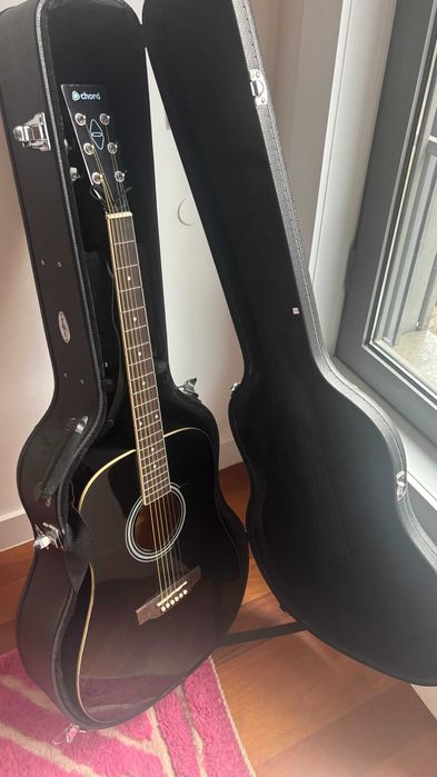 Violão acústico preto elegante com estojo rígido combinando.