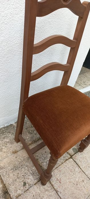 Cadeira em madeira com assento forrado em castanho escuro.
