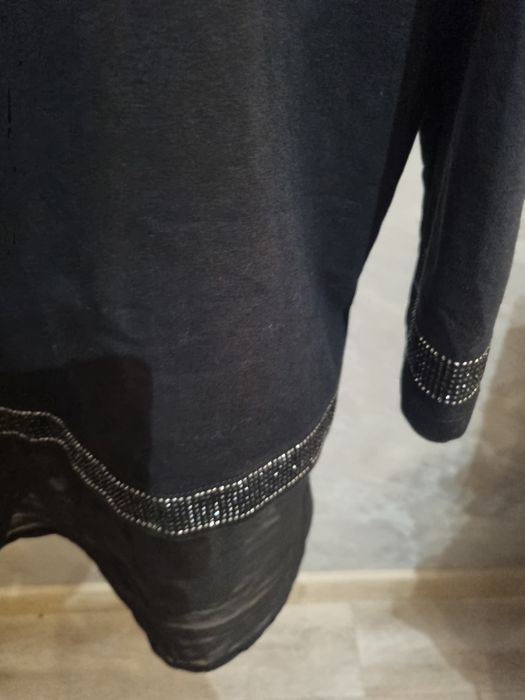 Śliczna czarna bluzka ozdobiona aplikacją w kształcie kota z cekinów.