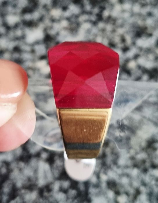 Anel dourado, em aço, com vermelho facetado na parte de cima. T17