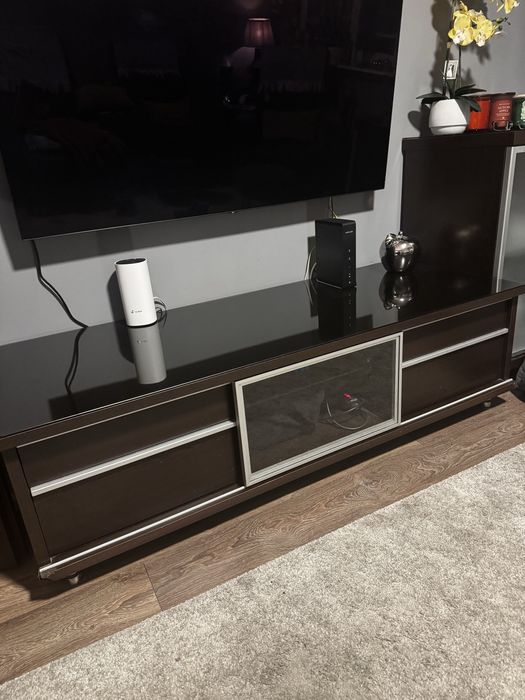 Czarna komoda RTV ze szklanym blatem.