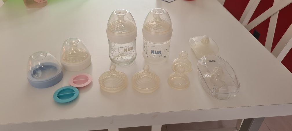 Butelki ze smoczkami firmy NUK oraz nakładki do karmienia piersią