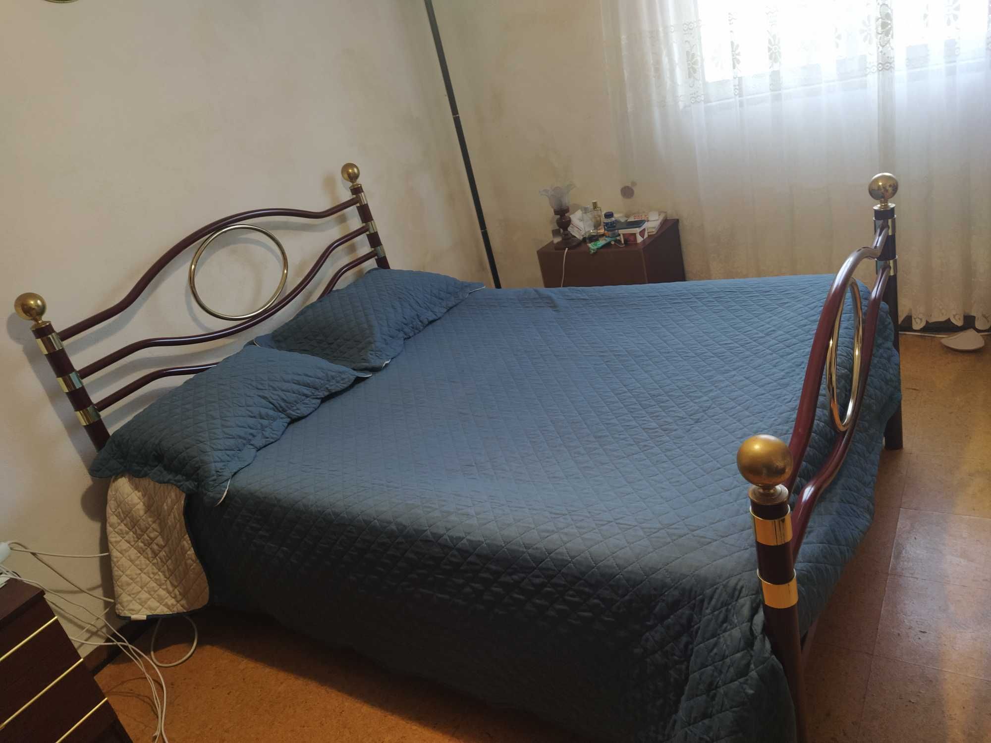 Cama de Casal em ferro com colchão e mesas de cabeceira.
