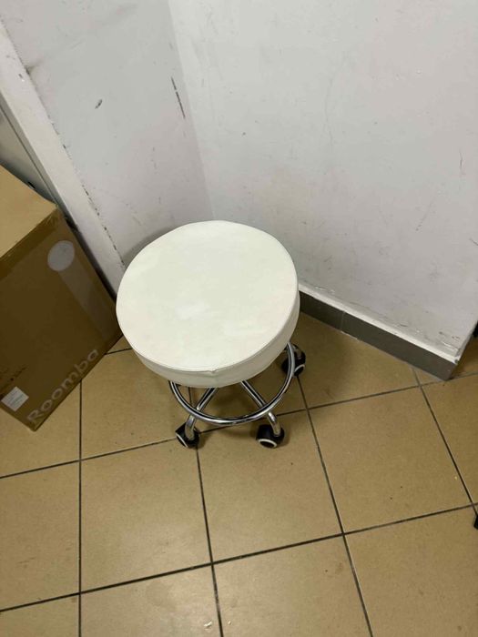 Biały, okrągły stołek na kółkach fryzjerski