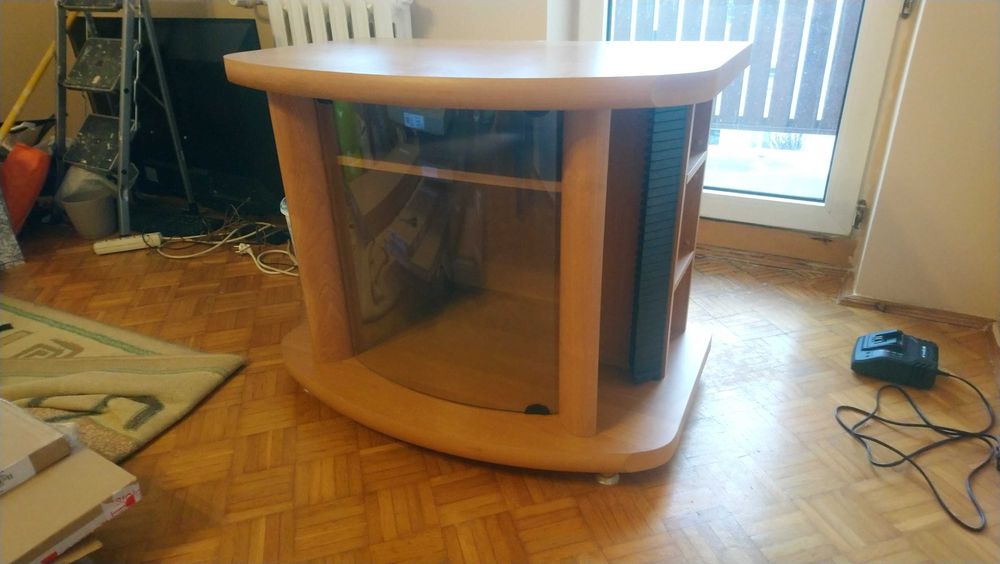 Szafka RTV do salonu w kolorze jasnego drewna ze szklaną witryną.