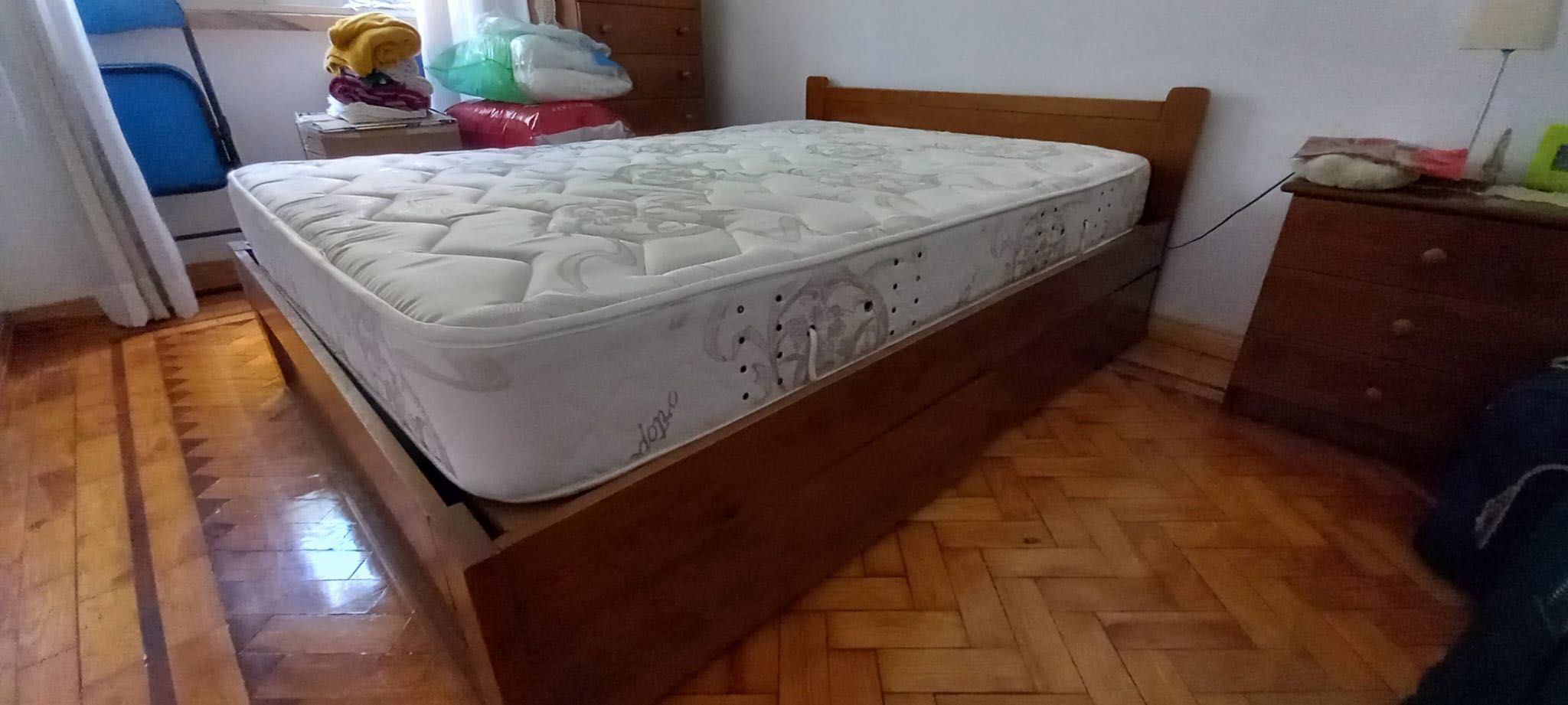 Cama de casal de madeira com colchão e mesa de cabeceira