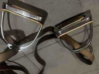 Um par de estribos metálicos com suspensões em couro