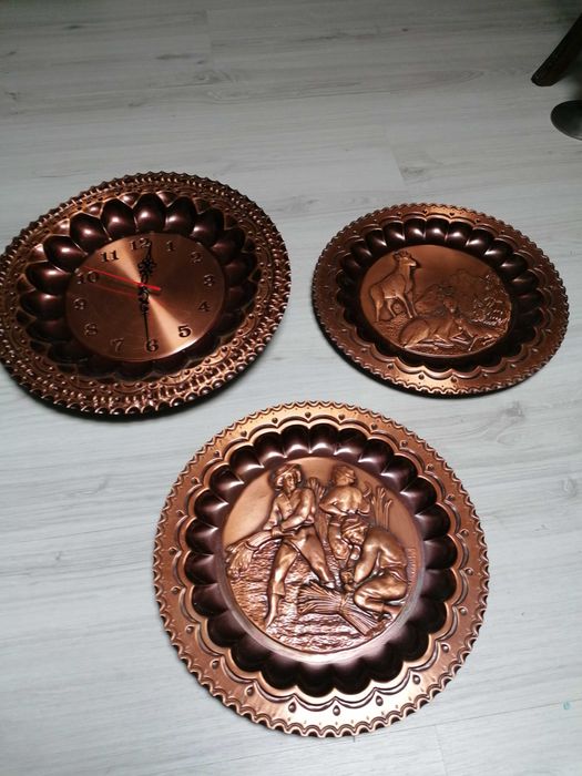 Pratos decorativos em cobre, sendo que um é relógio de parede.
