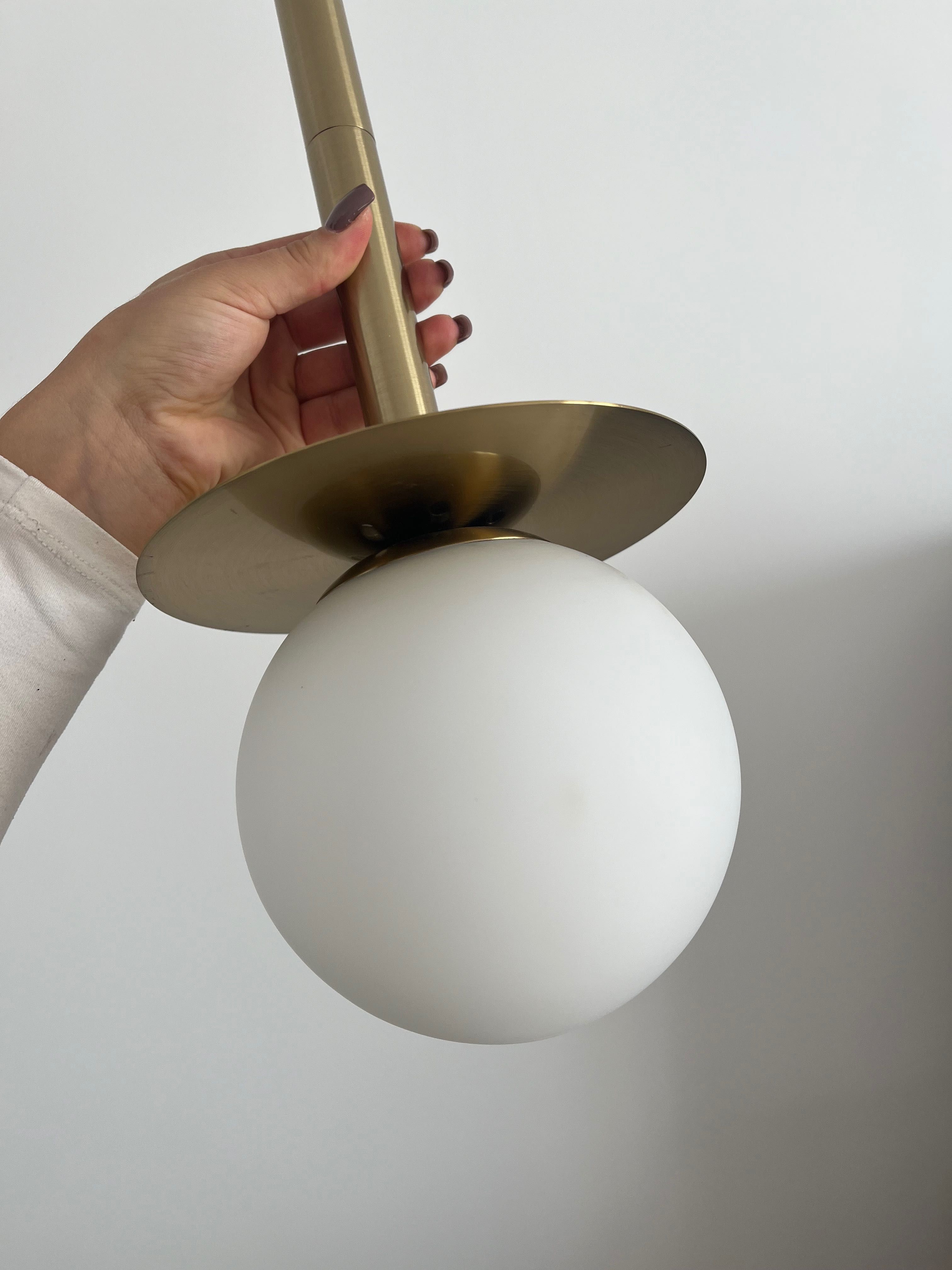 Złota lampa z białą kulą