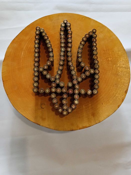 Герб України на зрізі дерева вибиті із стреляних гільз.