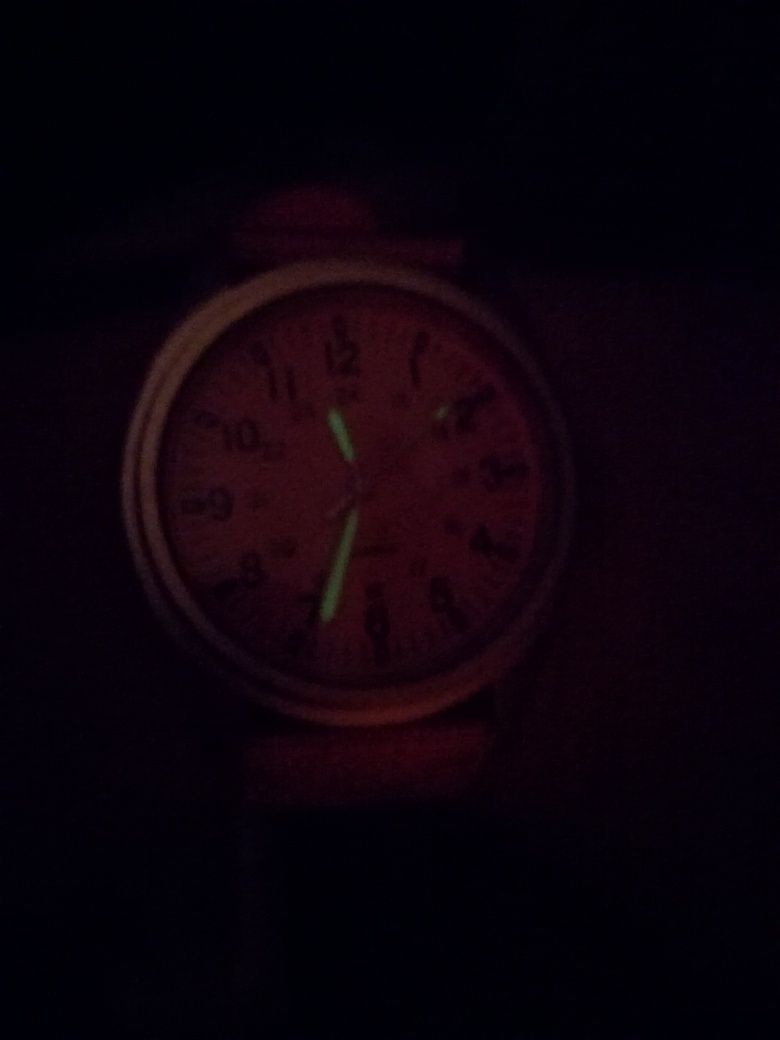 Relógio rosa tipo aviador com ponteiros que brilham no escuro