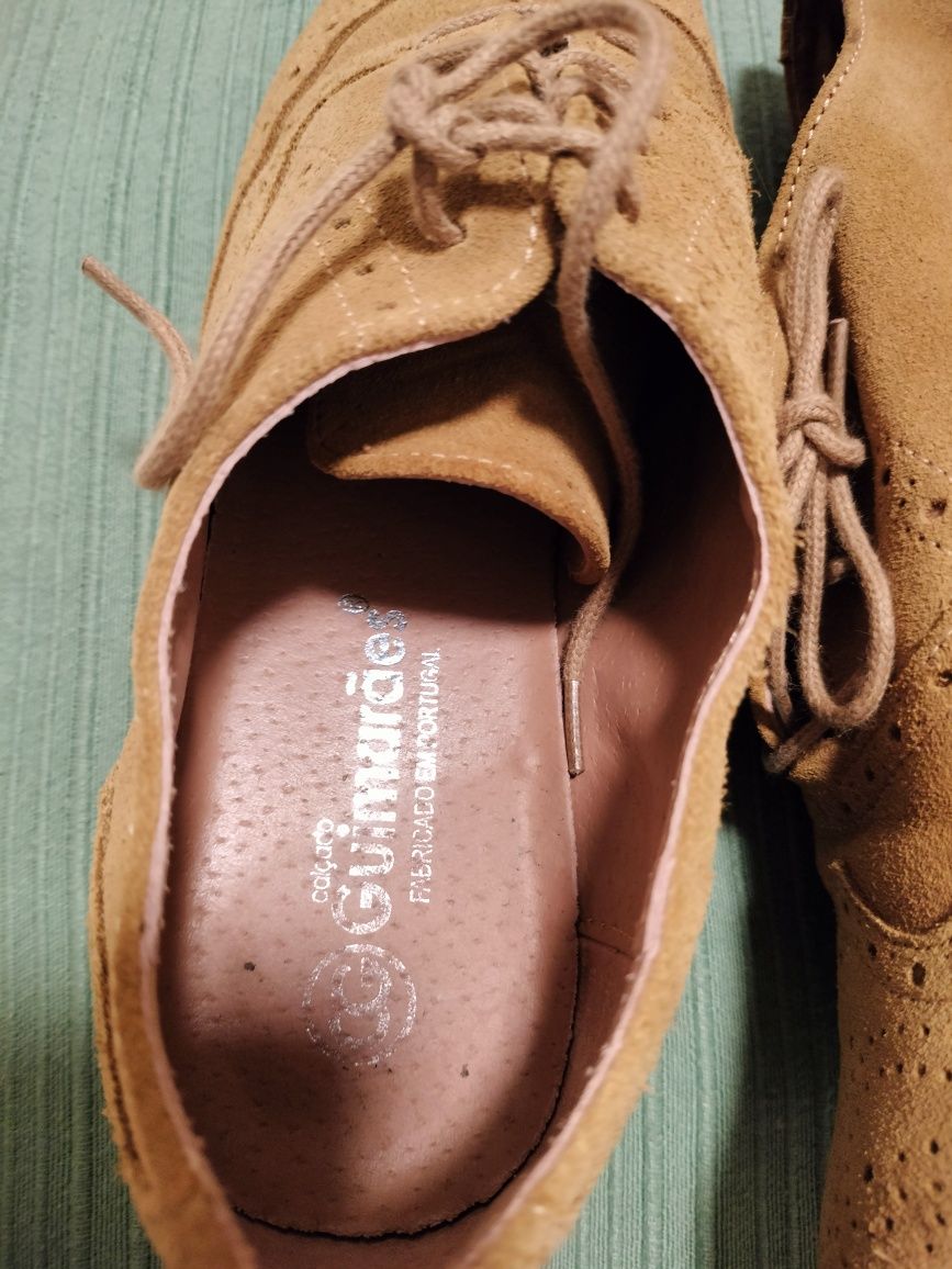 Sapatos com biqueira rdonda com atacadores em tecido tipo camurça.