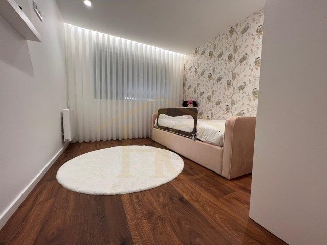 Móveis lacados cinzentos e cama cor de rosa com colchão e estrado