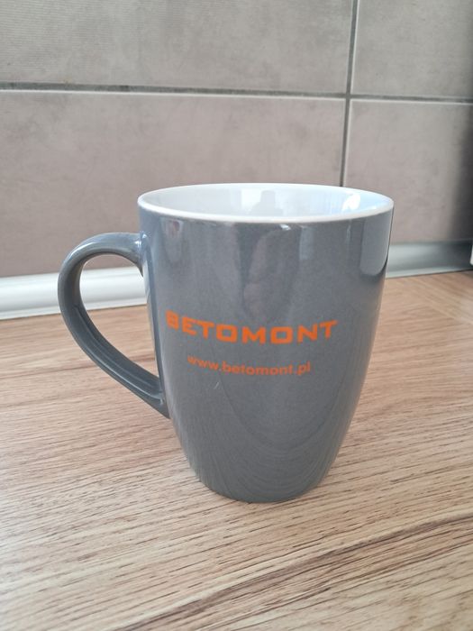 Szary kubek z napisem firmowym