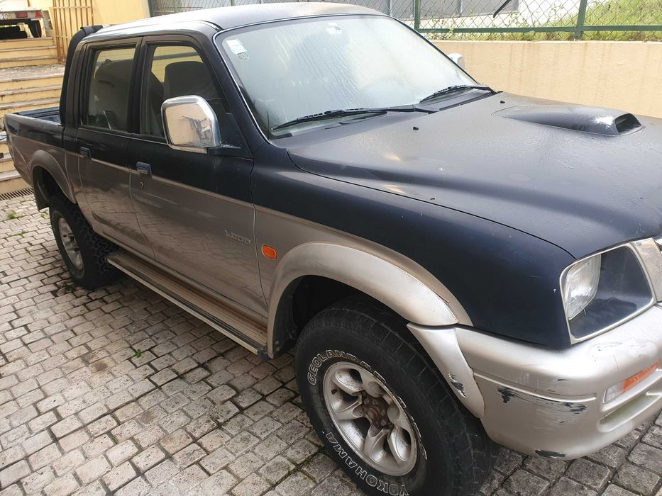 Mitsubishi L200 preta e prateada com engate de reboque