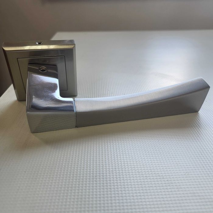 Nowa, elegancka klamka drzwiowa na kwadratowym szyldzie.