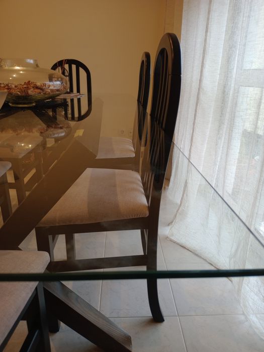 Mesa de vidro com 6 cadeiras estofadas a beje.