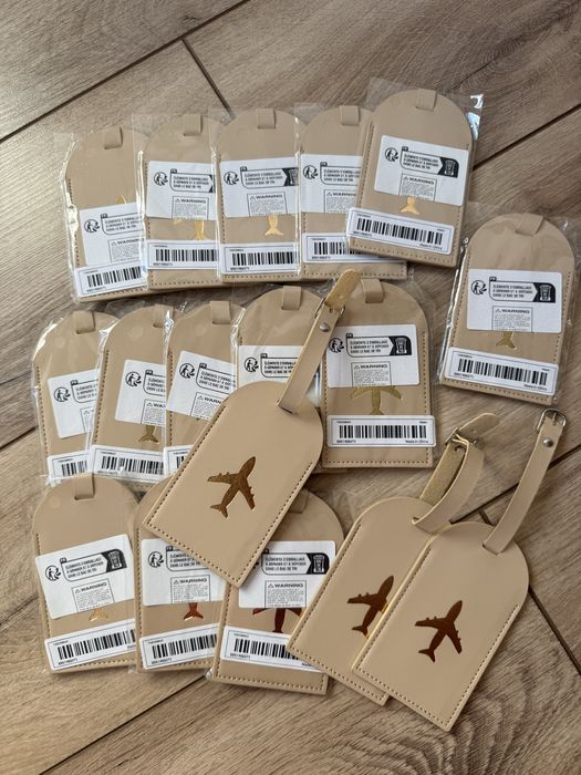 17 Beżowych zawieszek na bagaż ze złotym samolotem - prezent