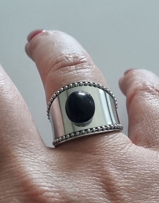 Anel prateado, em aço  com pedra preta oval. Ajustável