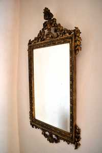 Espelho antigo com moldura dourada.