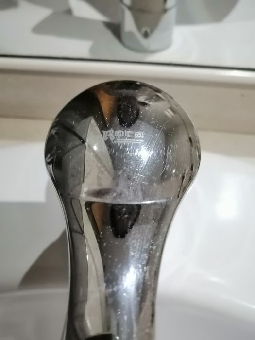 Lavatório branco com pedra de cor beje torneira misturadora.