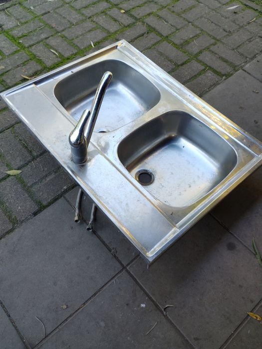 Zlewozmywak stalowy z baterią i przewodami.