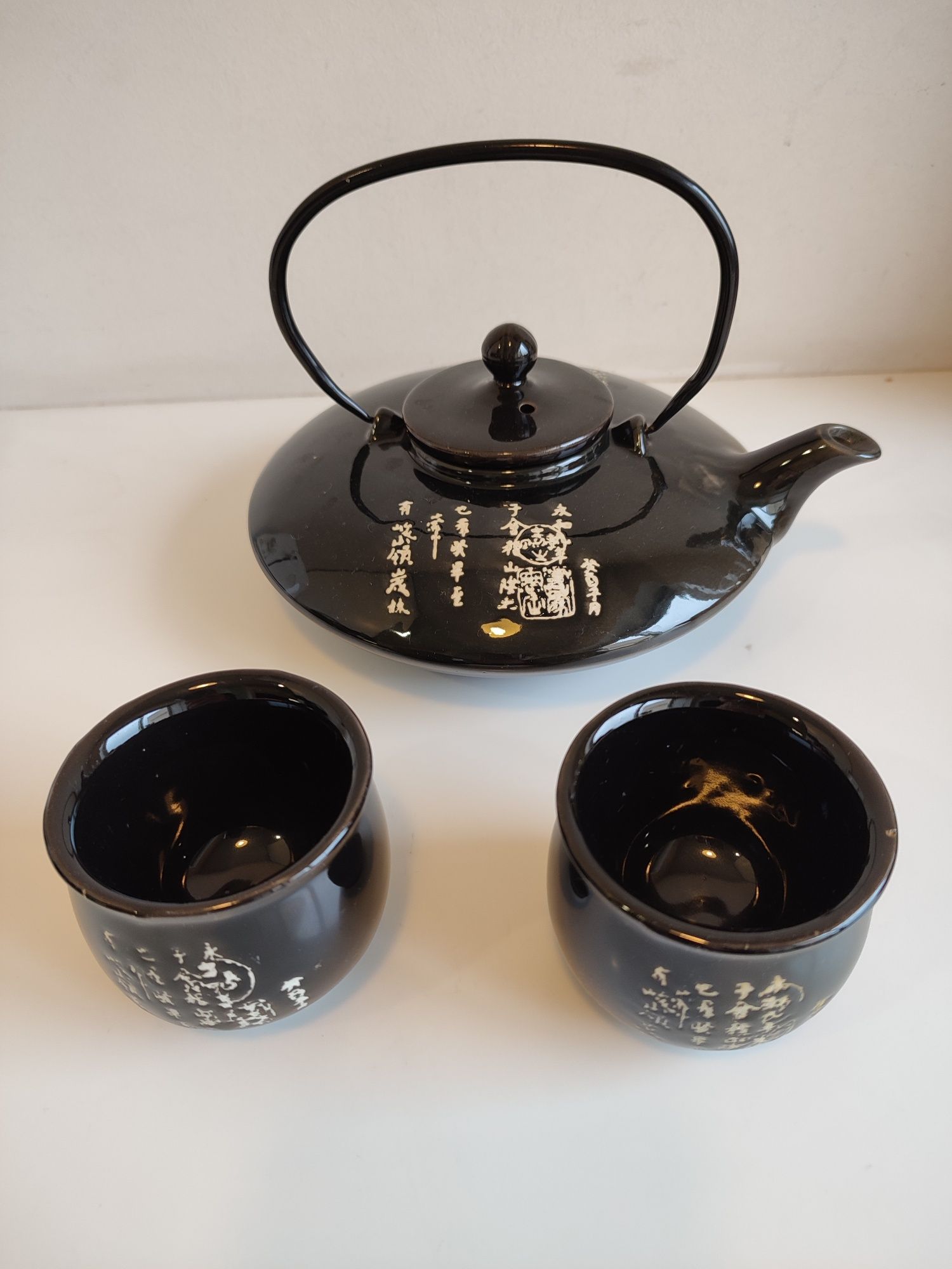 Conjunto de chá oriental com bule e dois copos.