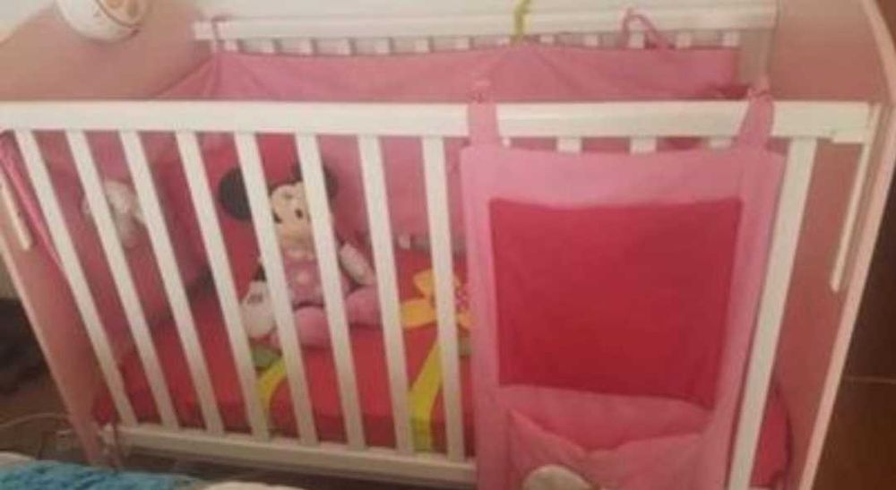 Cama de bebé rosa com colchão