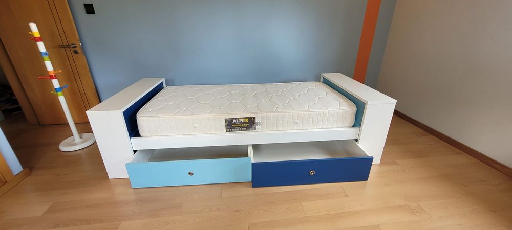 Cama com gavetões, colchão e cabide. Cores em tons de azul.