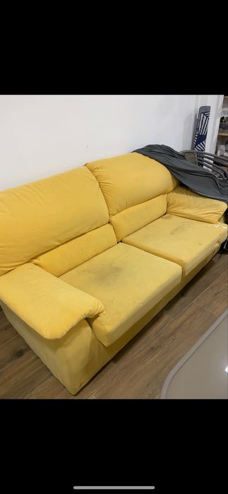 Sofá amarelo a precisar de limpeza.