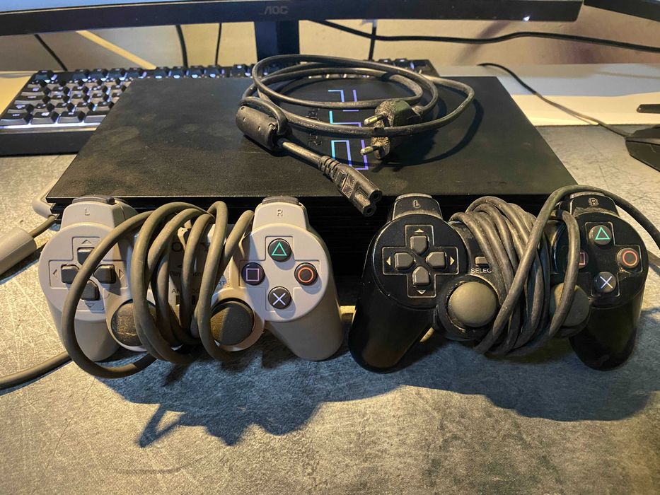PS2 com dois comandos e vários jogos.