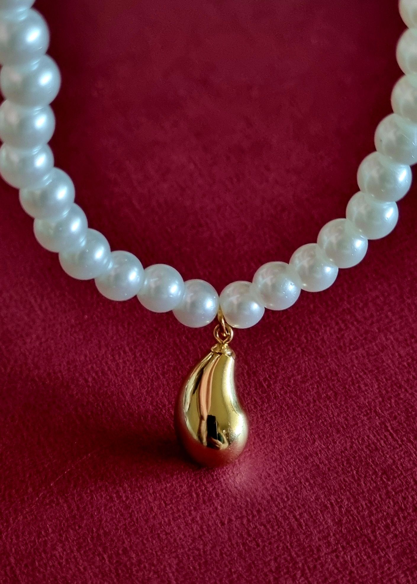 Colar de pérolas com acabamento e pingente em forma de gota, em aço.