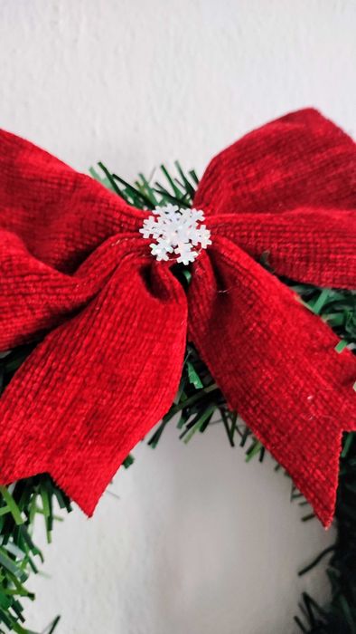 Wianek świąteczny na drzwi z czerwoną kokardą i białym reniferem