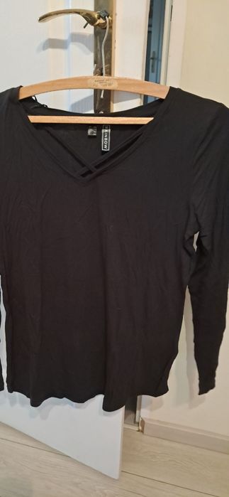 Czarna bluzka z ozdobnym dekoltem.