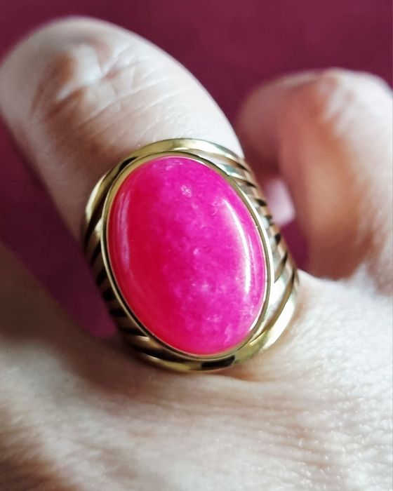 Anel dourado, em aço, com pedra oval rosa fucsia. 18/ajustável