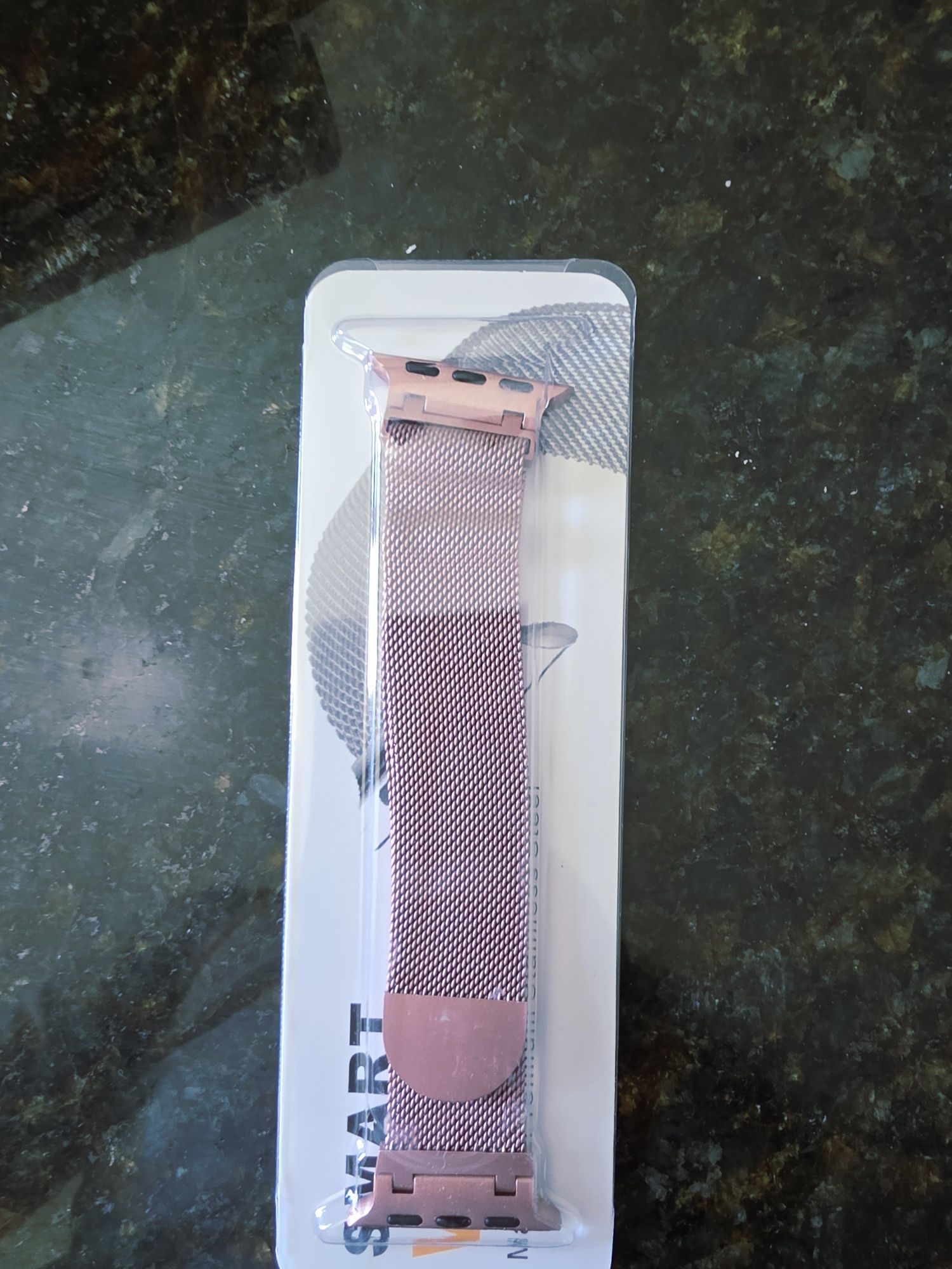 O produto na imagem é uma bracelete metálica em malha milanesa, de cor