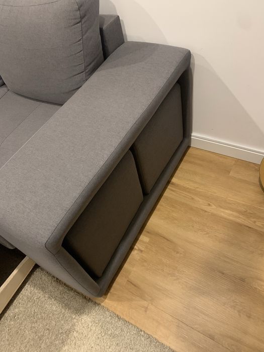Sofa cama cinza com arrumaçao e dois bancos.
