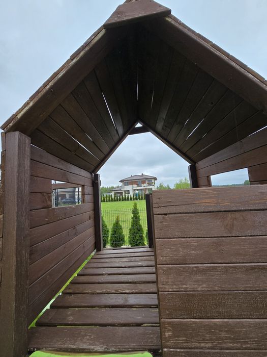 Drewniany plac zabaw z domkiem, zjeżdżalnią, huśtawką i ścianką wspina