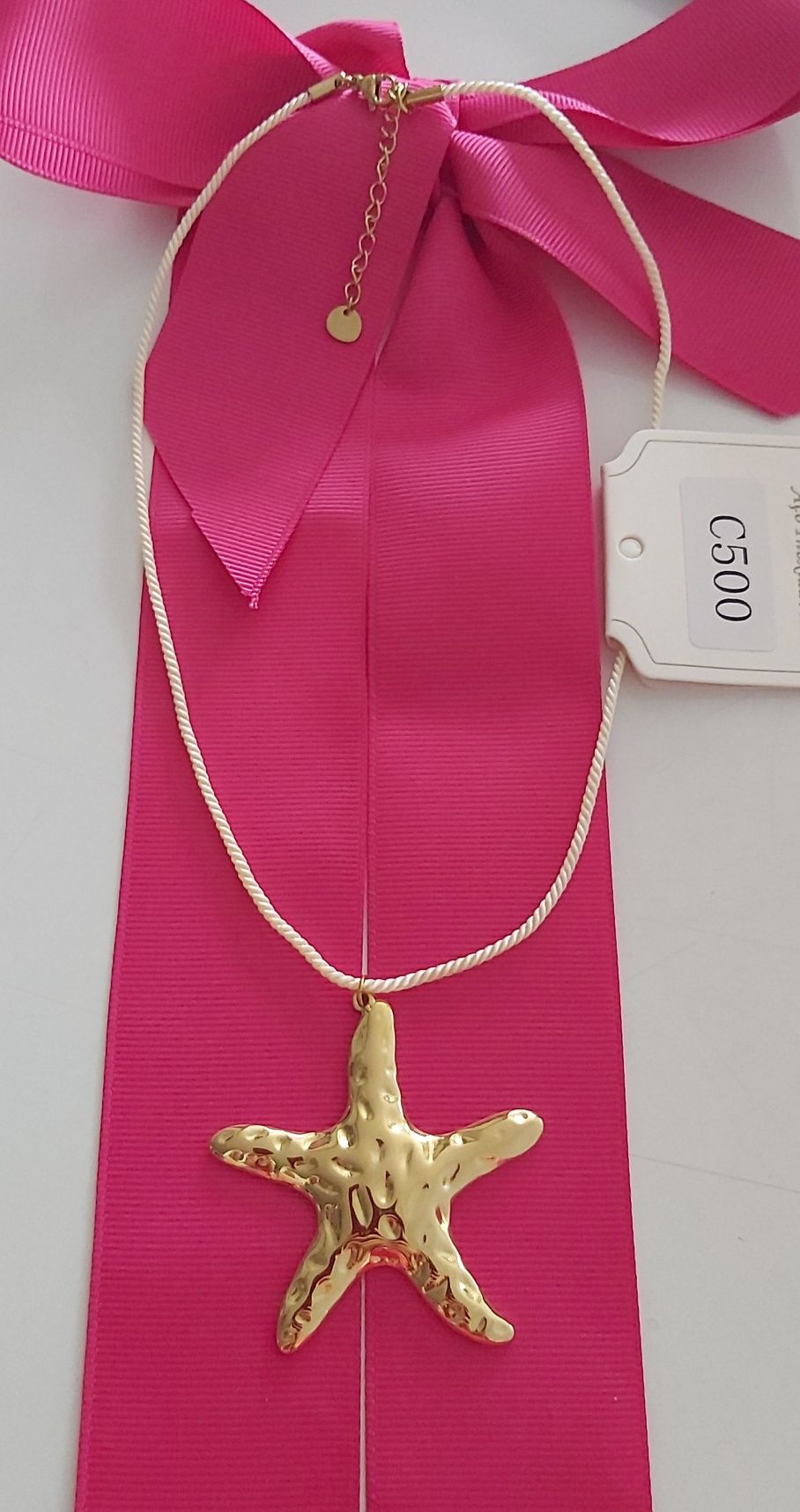 Colar dourado, em aço, com pingente em forma de estrela. Tem extensor