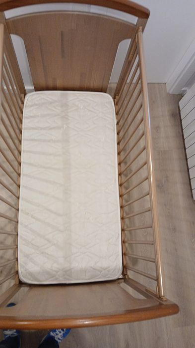 Cama de bebê, em madeira, cor bege.