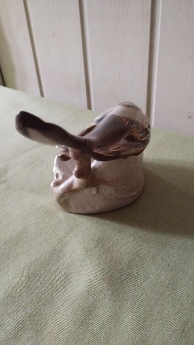 Porcelanowa figurka sroki na krawędzi podstawy.