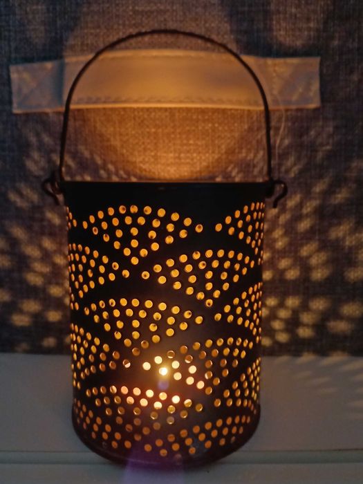 Stylowa latarnia z czarnej blachy ze złotym wnętrzem.