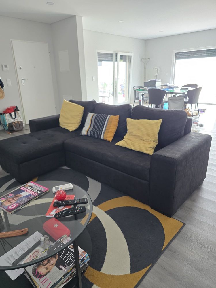 Sofa cinza escuro com arrumos e cama