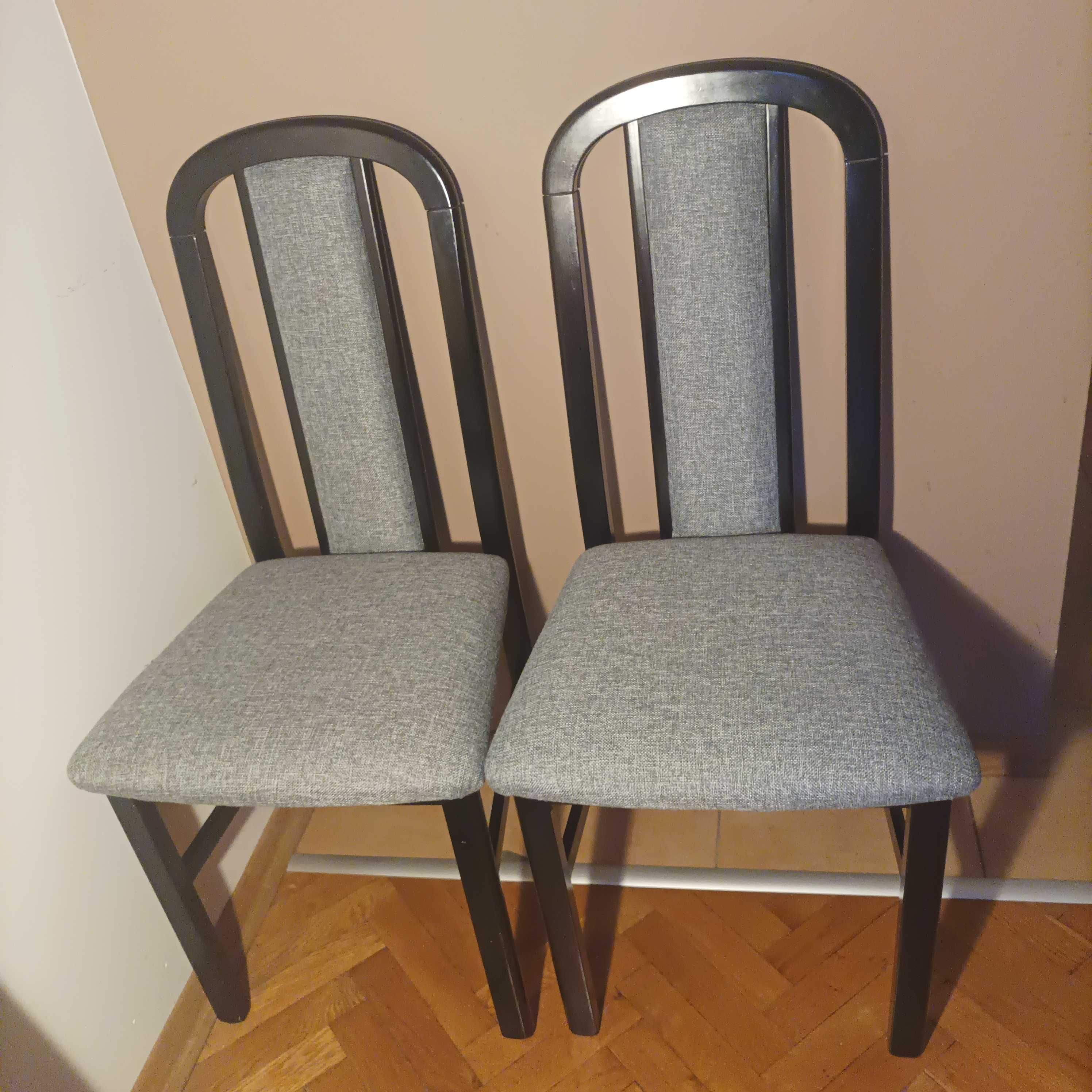 Dwa drewniane czarne krzesła z szarą tapicerką